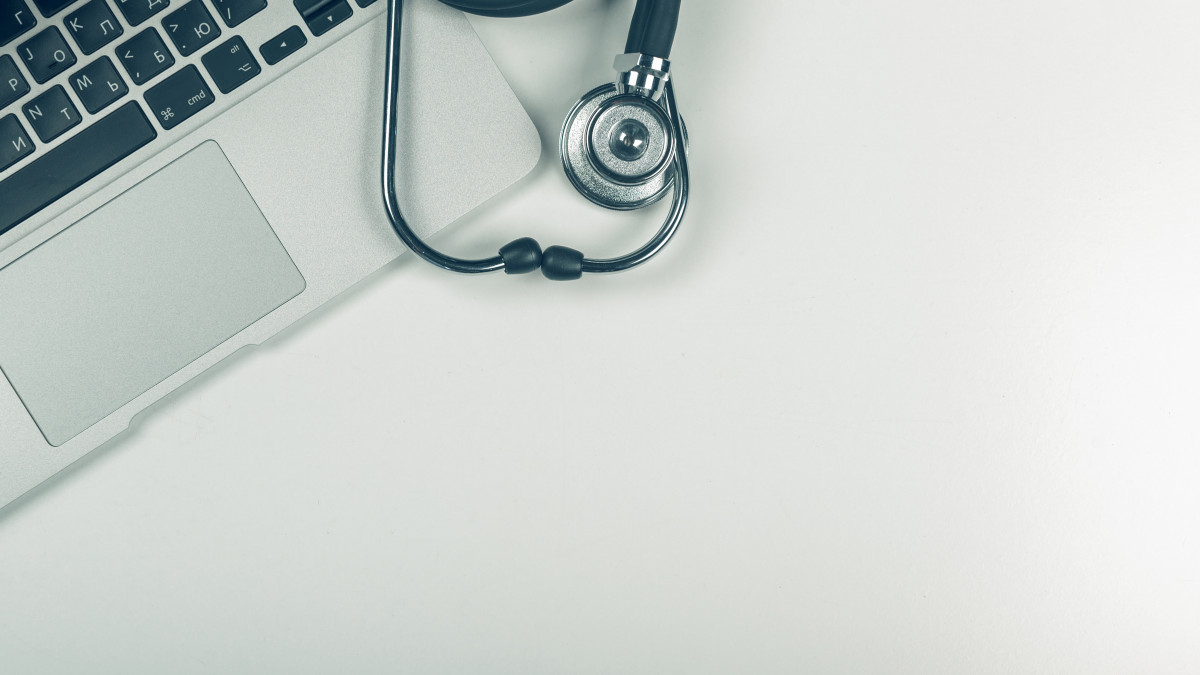 Un stetoscope est posé juste à côté d'un ordinateur portable sur une table blanche.